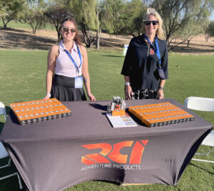 Two RCI sales representatives stand behind a table with several giveaways during a golf outing in Arizona.